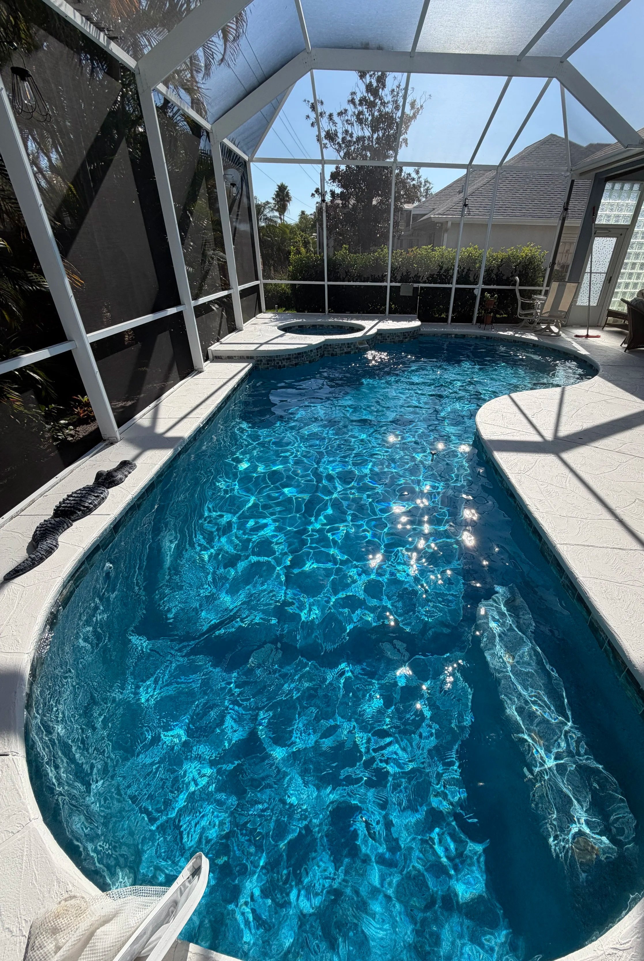 Person with a straw sunhat sitting poolside with legs extended into the pool, viewed from above.
