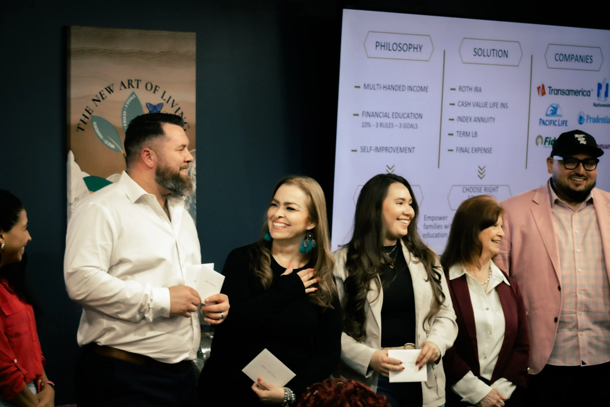 A group of people standing in front of a presentation screen, smiling and engaging with each other during a professional event.