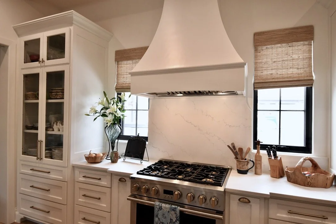 Contemporary kitchen with white cabinetry, wood accents, and woven wood shades.