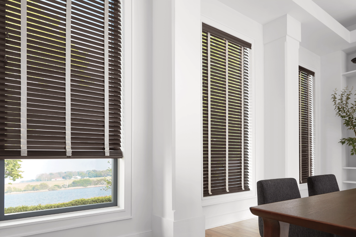 Hunter Douglas Parkland® Wood Blinds covering three dining room windows.