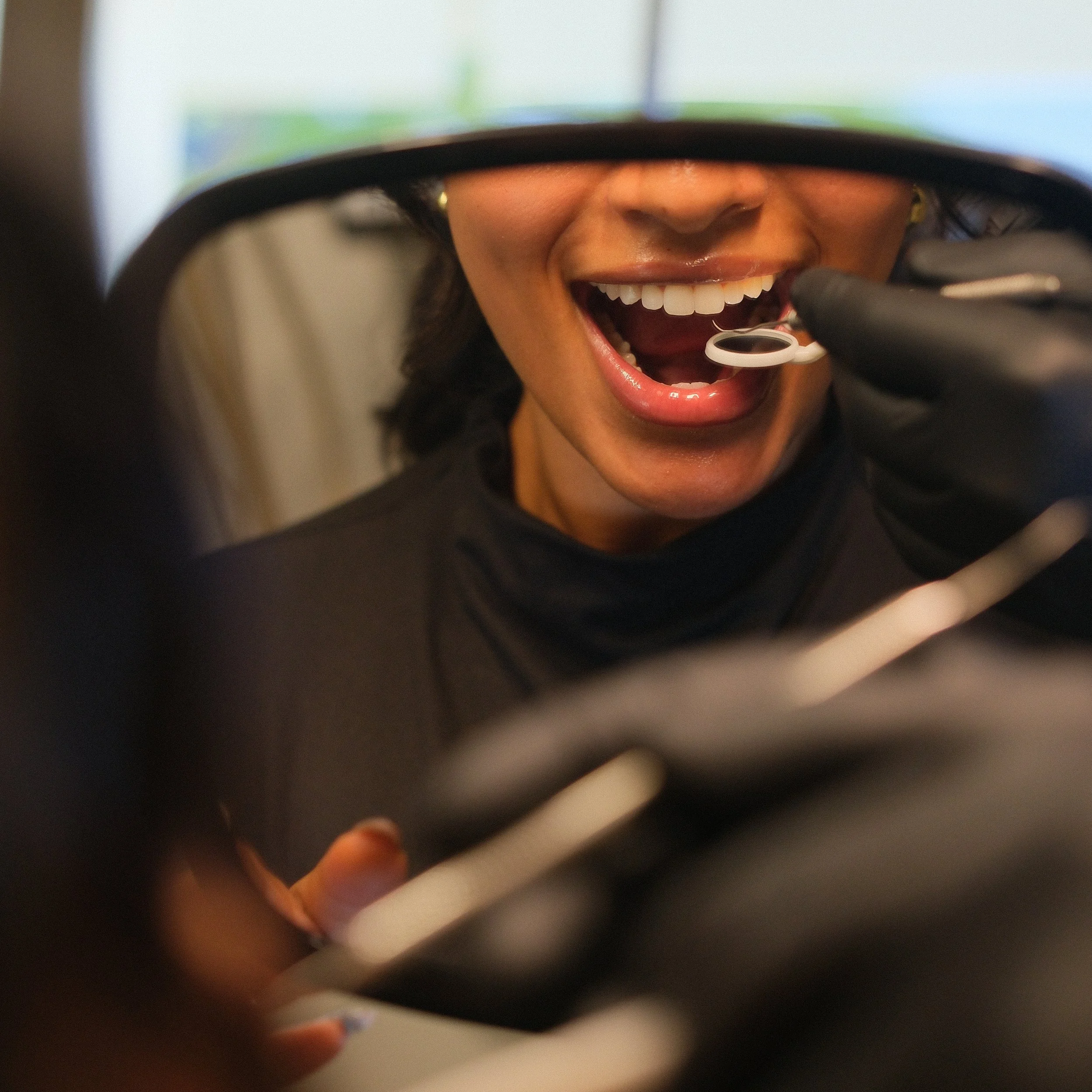 Close-up of a person receiving a dental check-up, with a dentist using dental tools near the patient's open mouth.