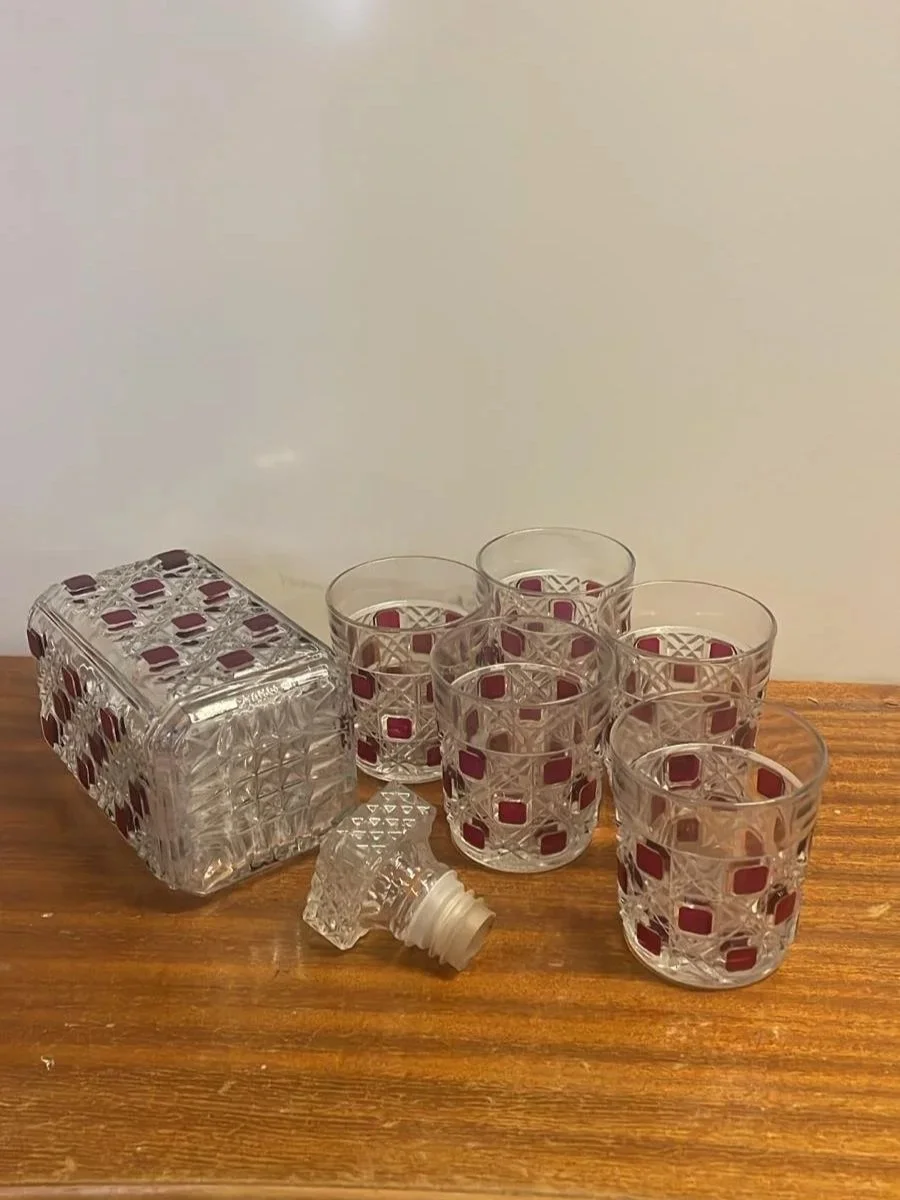 Vintage Luminarc Damier -karahvisetti: neliskulmainen kirkas lasikarahvi ja viisi juomalasia, joissa on punaisia neliökuvioita ja perinteinen hiottu ruutupinta."