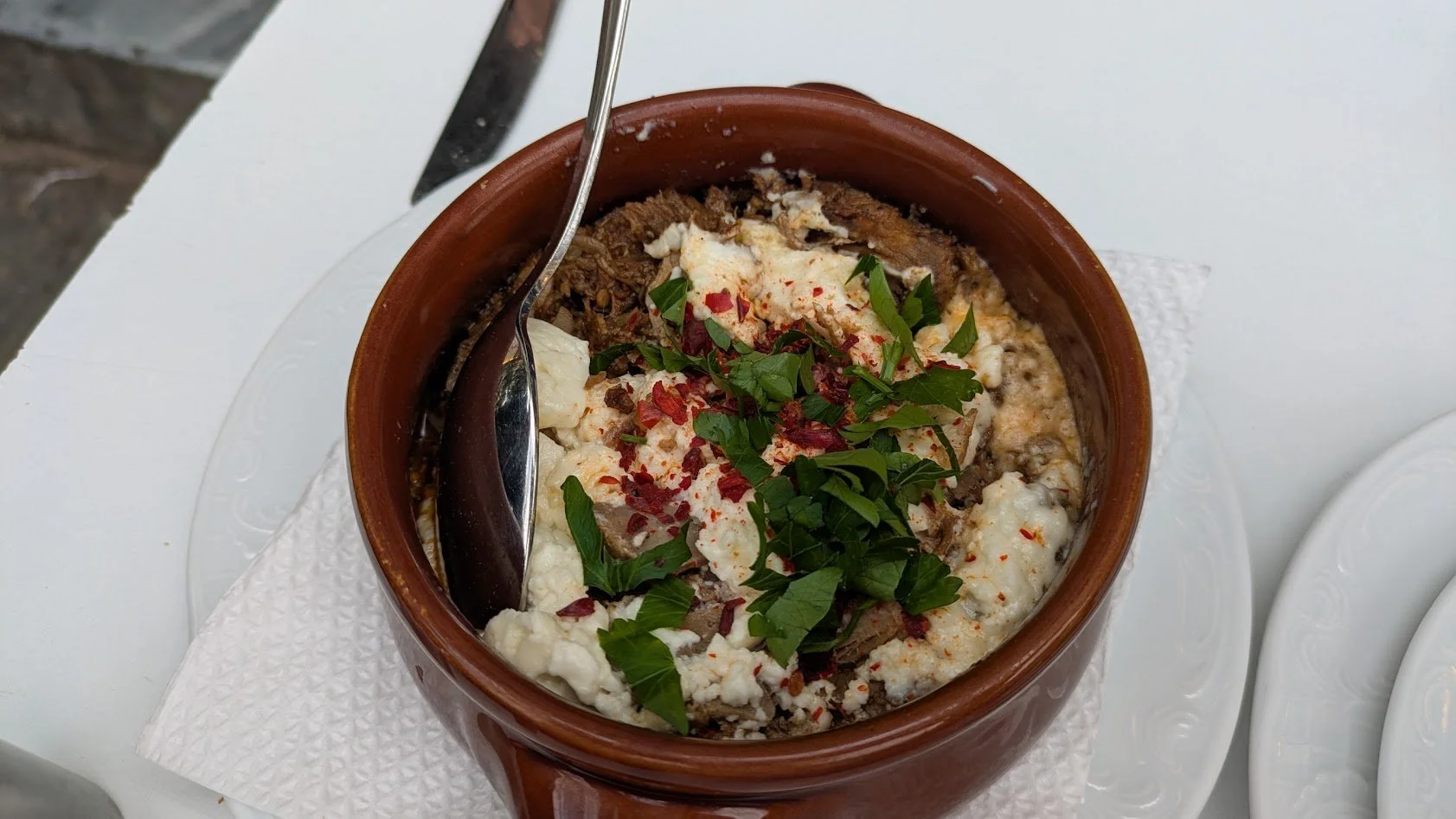 Kavourmas - a traditional Greek slow-cooked meat delicacy. Made from pork and beef,  the meat is salted ,and  simmered for hours in  spices (nutmeg, clove, allspice). It is a hearty, savory, and tender dish served in a clay pot topped with feta chees