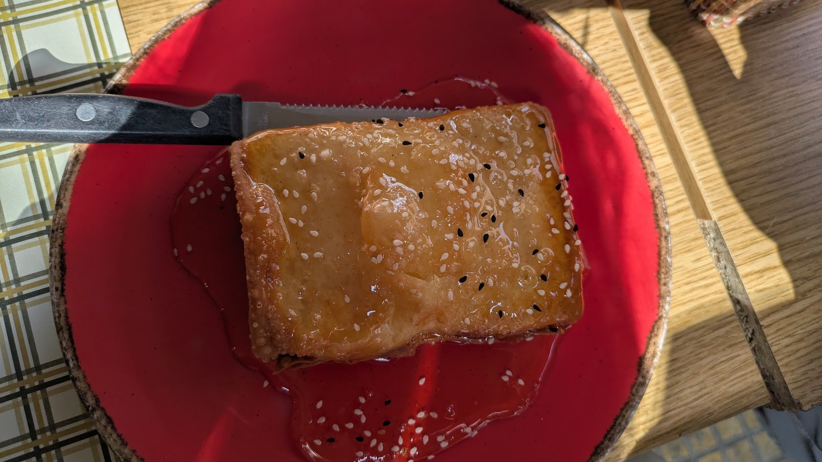 Feta me meli - an appetizer featuring a block of feta cheese wrapped in phyllo dough, baked or fried until golden and crisp, and drizzled with honey and sesame seeds. So stinking good!