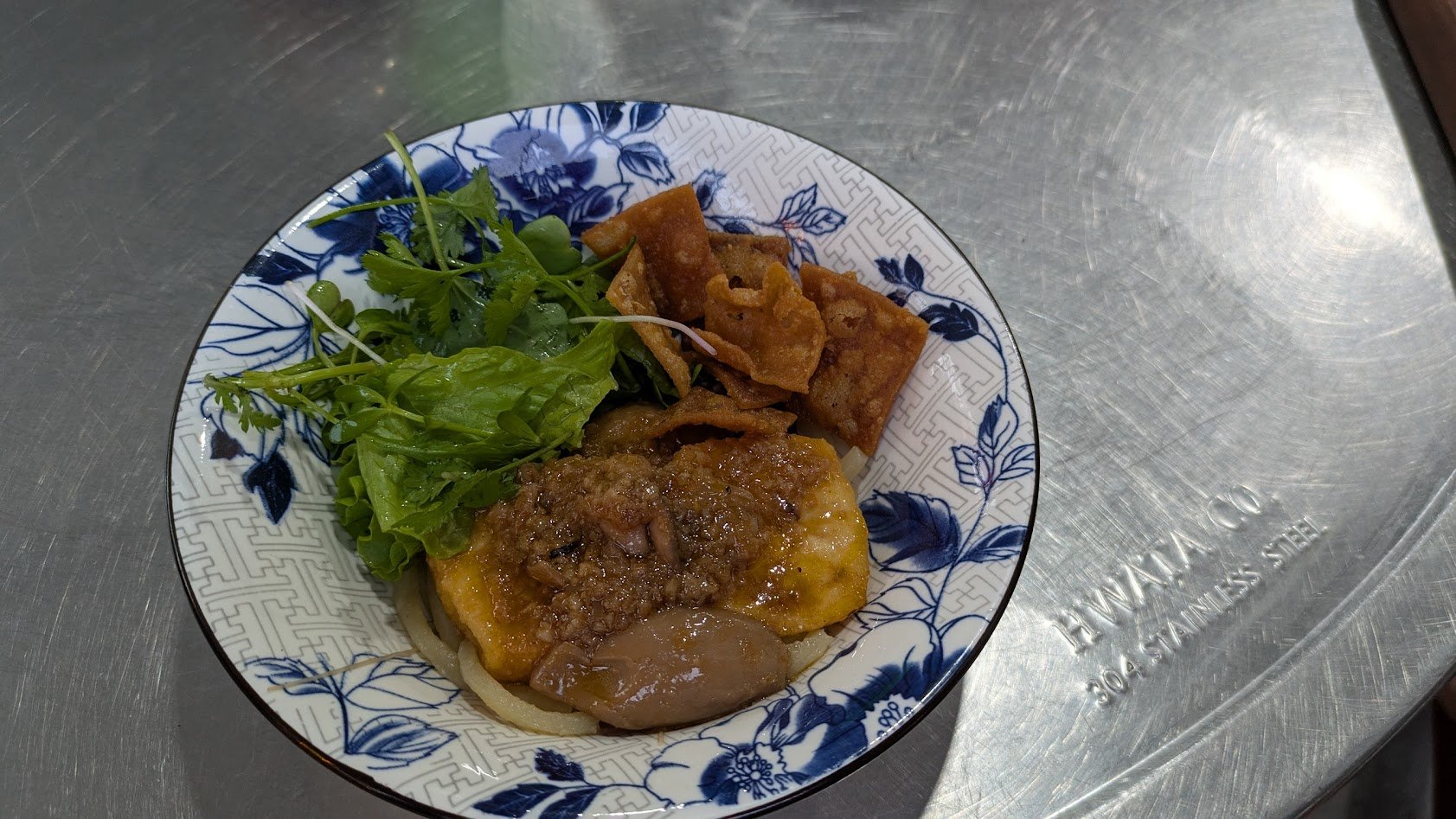 Cao Lau is a noodle dish made of thick, chewy rice noodles, pork, and herbs, served in a five-spice broth. It is unique to Hoi An because the traditional noodles are made using water from the ancient Ba Le well in Hoi An which is a 10th-century Cham-