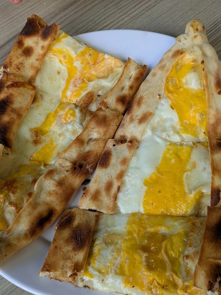 Kasarli yumurtali - Turkish cheese pide with egg. Pide is a a relatively thin, baked bread made from leavened dough, and topped with various combinations of ingredients. It reminded me a bit of the khachapuri in Georgia