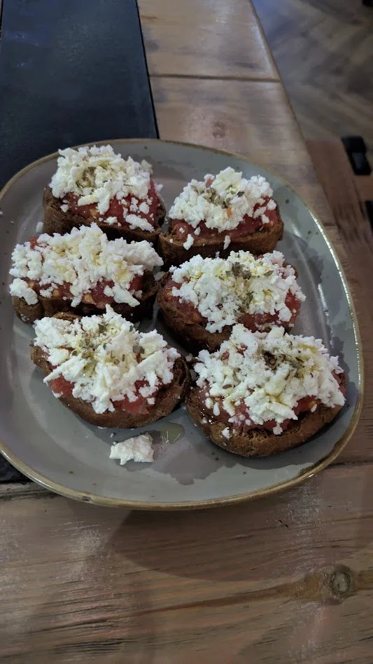 Dakos - A classic appetizer featuring a dry barley rusk topped with grated tomato, crumbled feta, olive oil, and herbs. It is basically Greece's version of bruschetta. It was seriously delicious!
