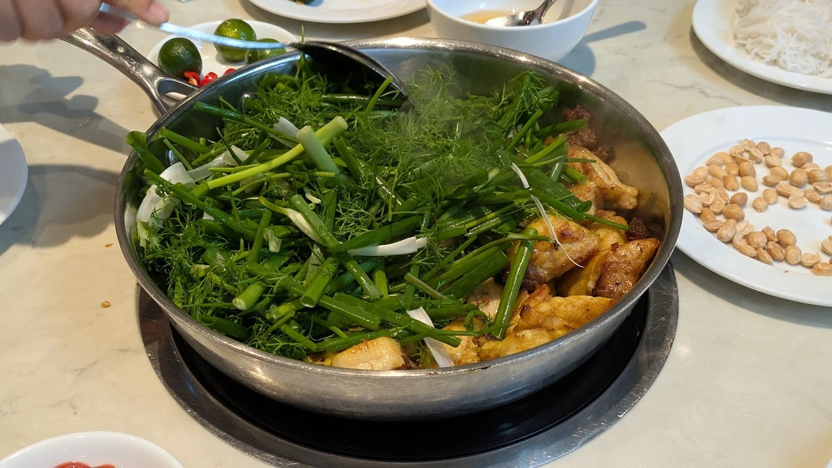 Cha Ca La Vong is a famous, historic Hanoi dish of marinated fish grilled and served sizzling with dill, scallions, rice noodles, herbs, peanuts, and shrimp paste. The fish was already cooked, then they threw everything else in the pan on a burner at