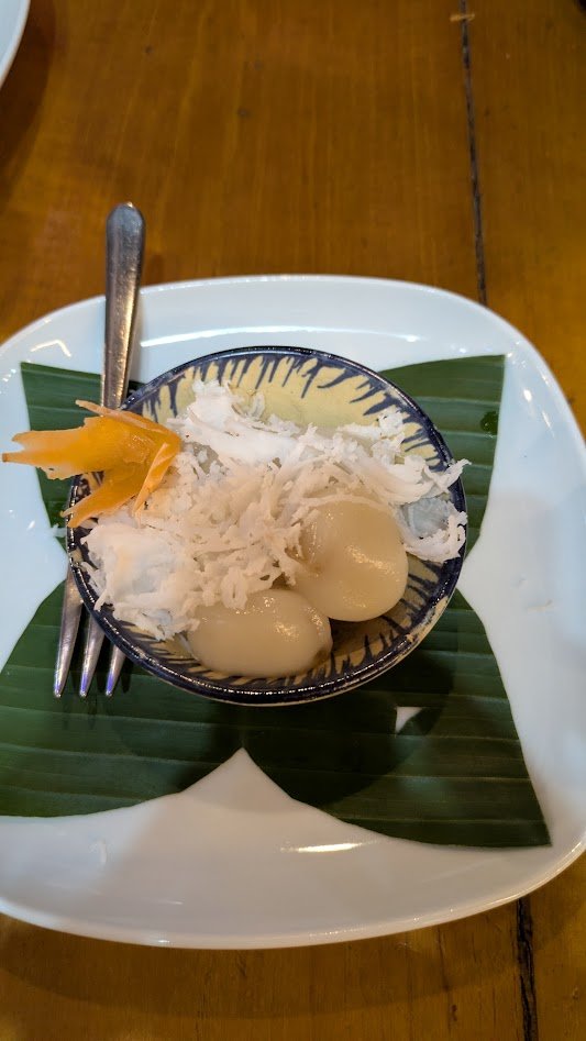 Nom Plae Ai - a popular traditional Cambodian dessert consisting of small, chewy, boiled glutinous rice balls filled with molten palm sugar and coated in grated coconut. We had these in a little village at a road side stand, and Grady made them a sec