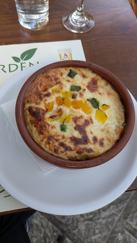 Moussaka - A traditional Greek casserole with layers of sautéed eggplant, potatoes, and a savory minced lamb or beef, topped with a creamy béchamel sauce and cheese, then baked in a little crock pot. It is a super popular "Greek comfort food," common