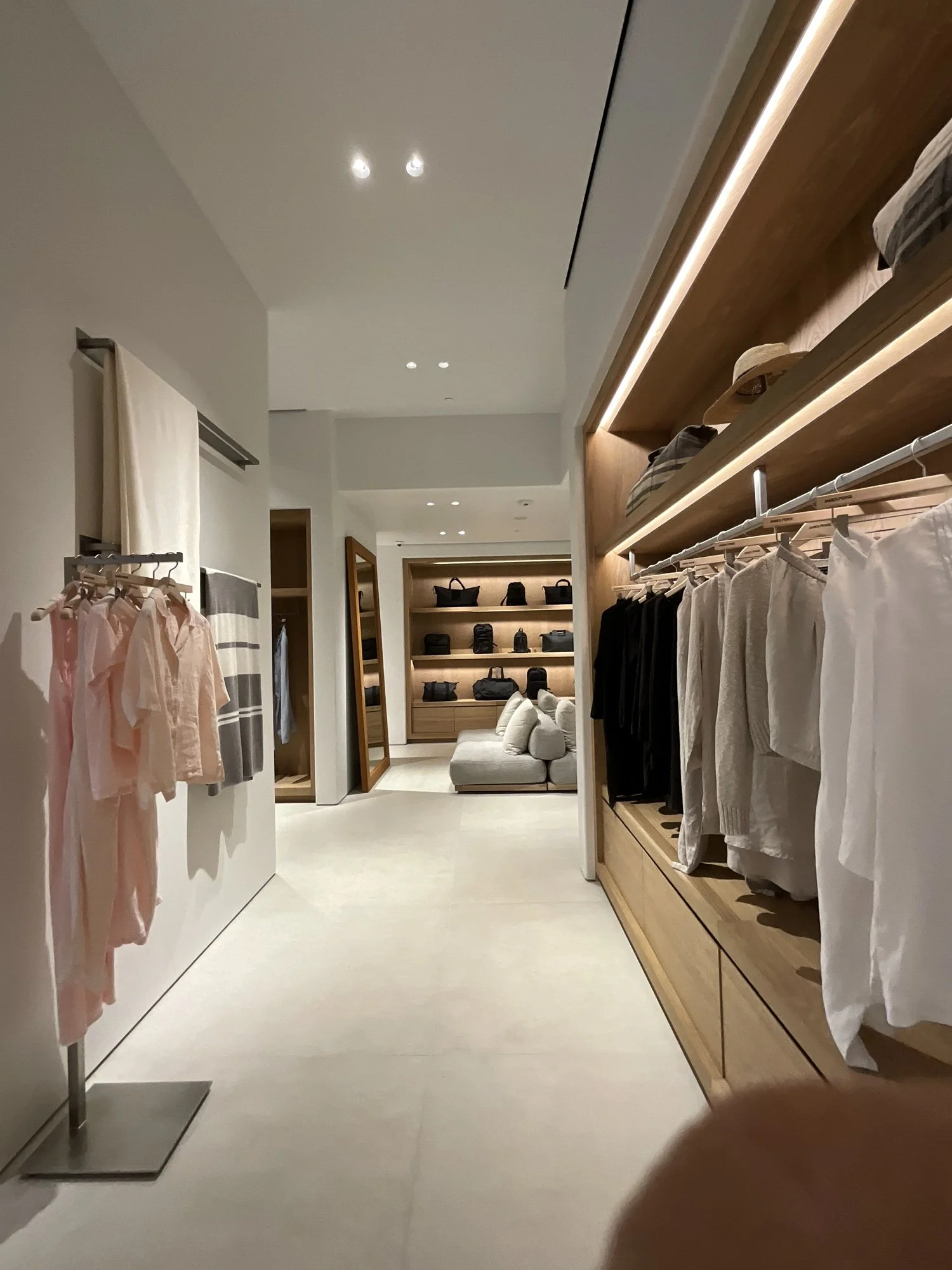 Mirrored James Perse hallway with wood shelving and folded apparel displays