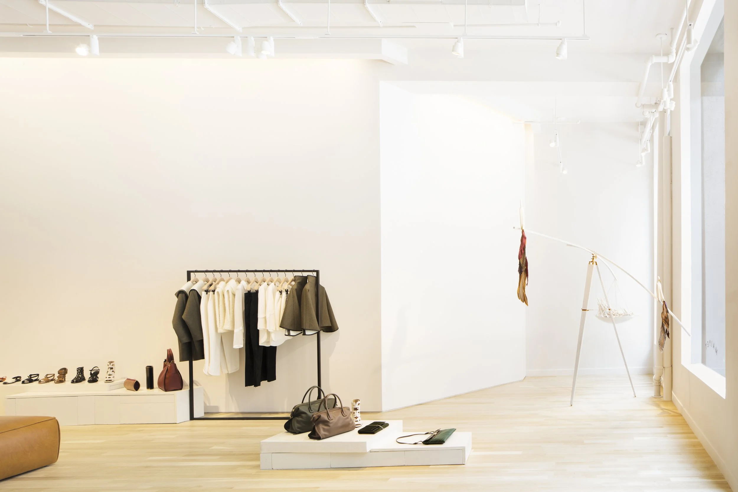 Minimalist white gallery space with clothing racks inside the Maiyet store
