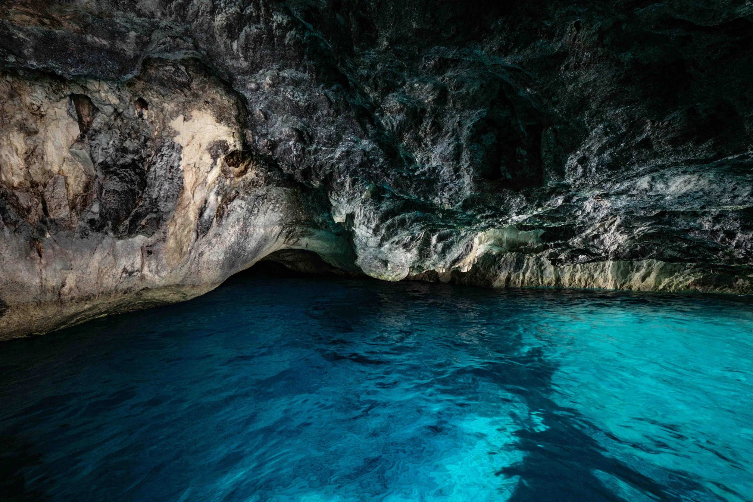A A shot inside hidden coastal cove with turquoise blue water sitting beneath an arch of granite rock in the Greek Cyclades.