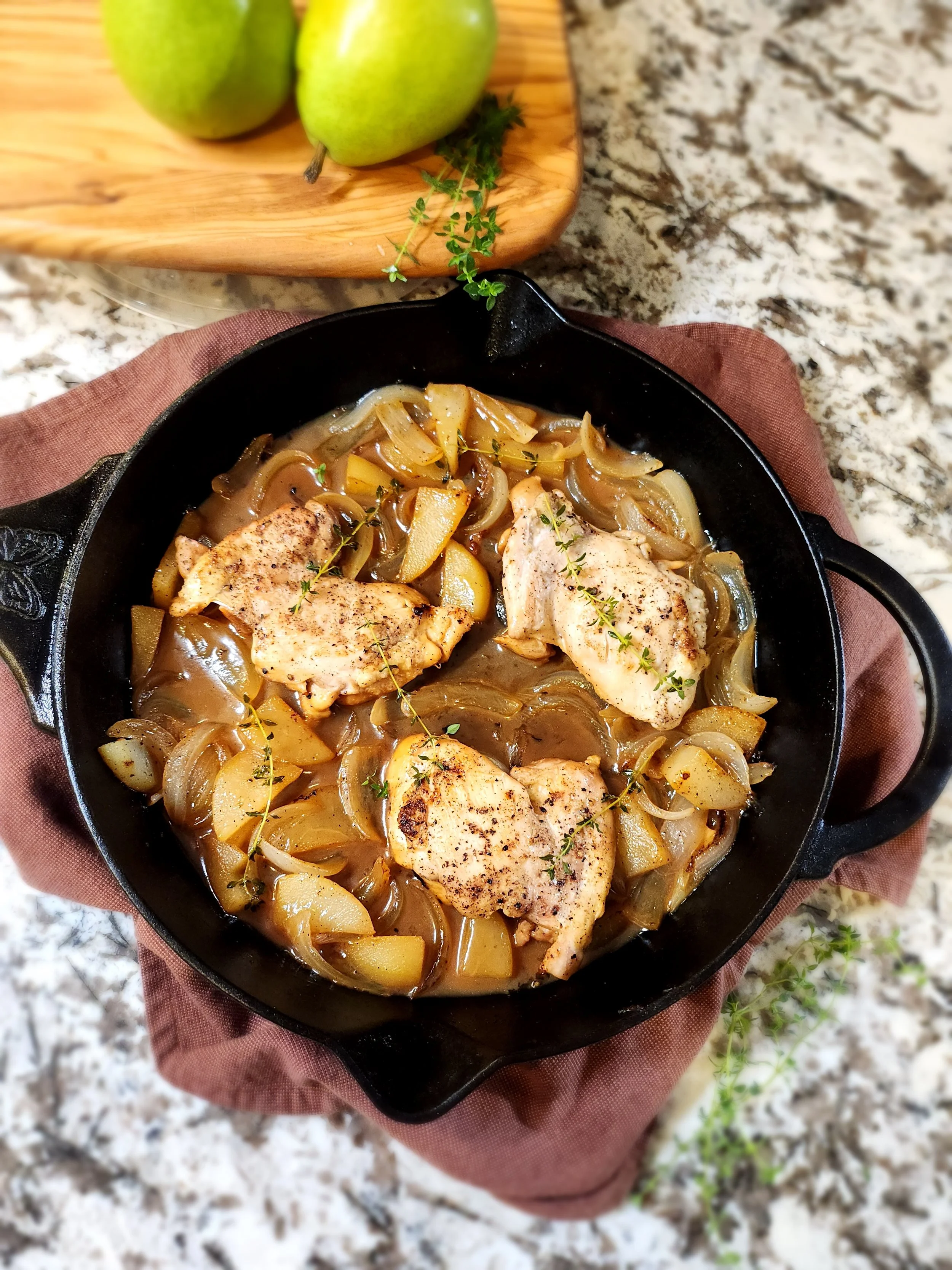 photo of  a cast iron with cooked chicken and pears