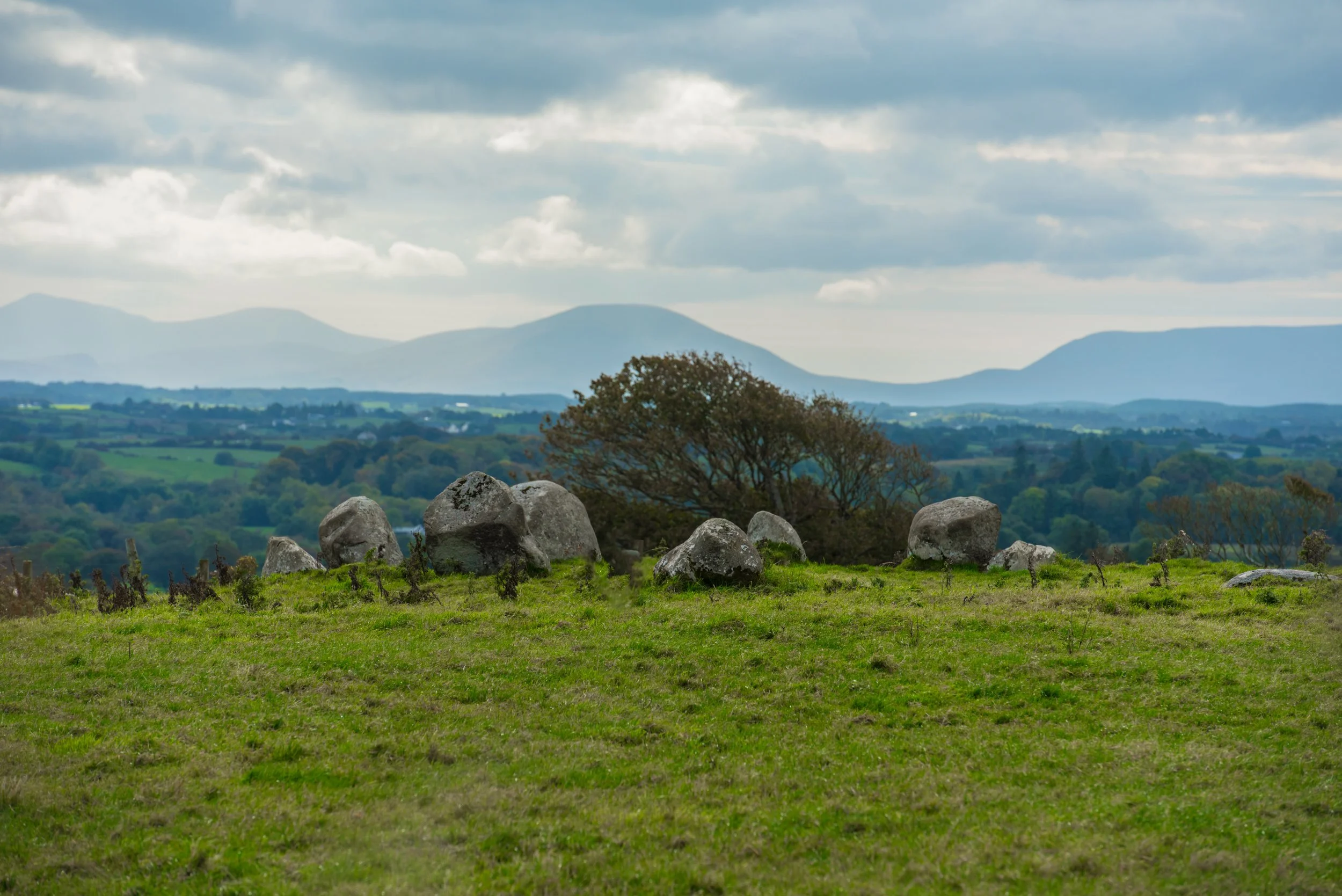 a neolithic stone circle in ireland with a mountain in the background