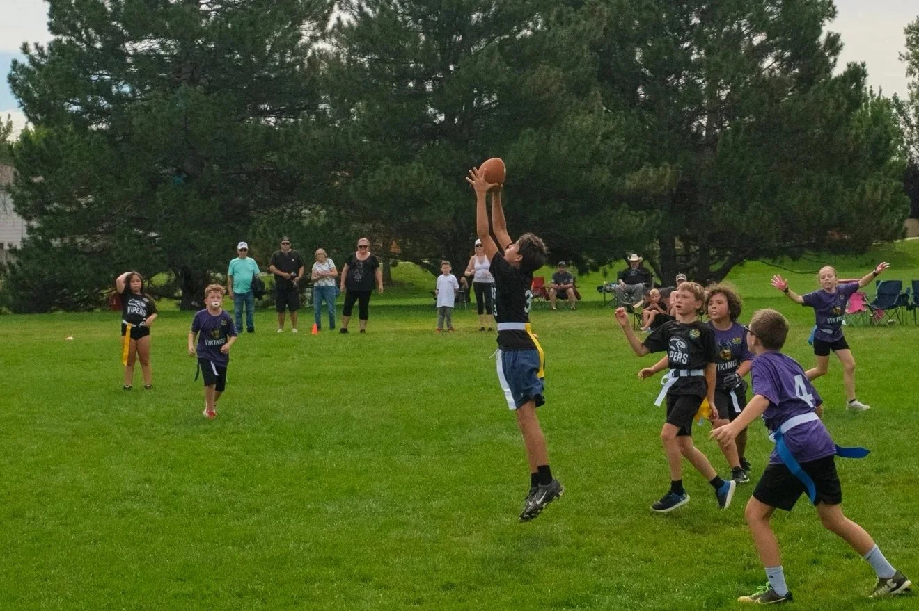 Children playing flag football on a grassy field in Westminster and Broomfield Colorado. 