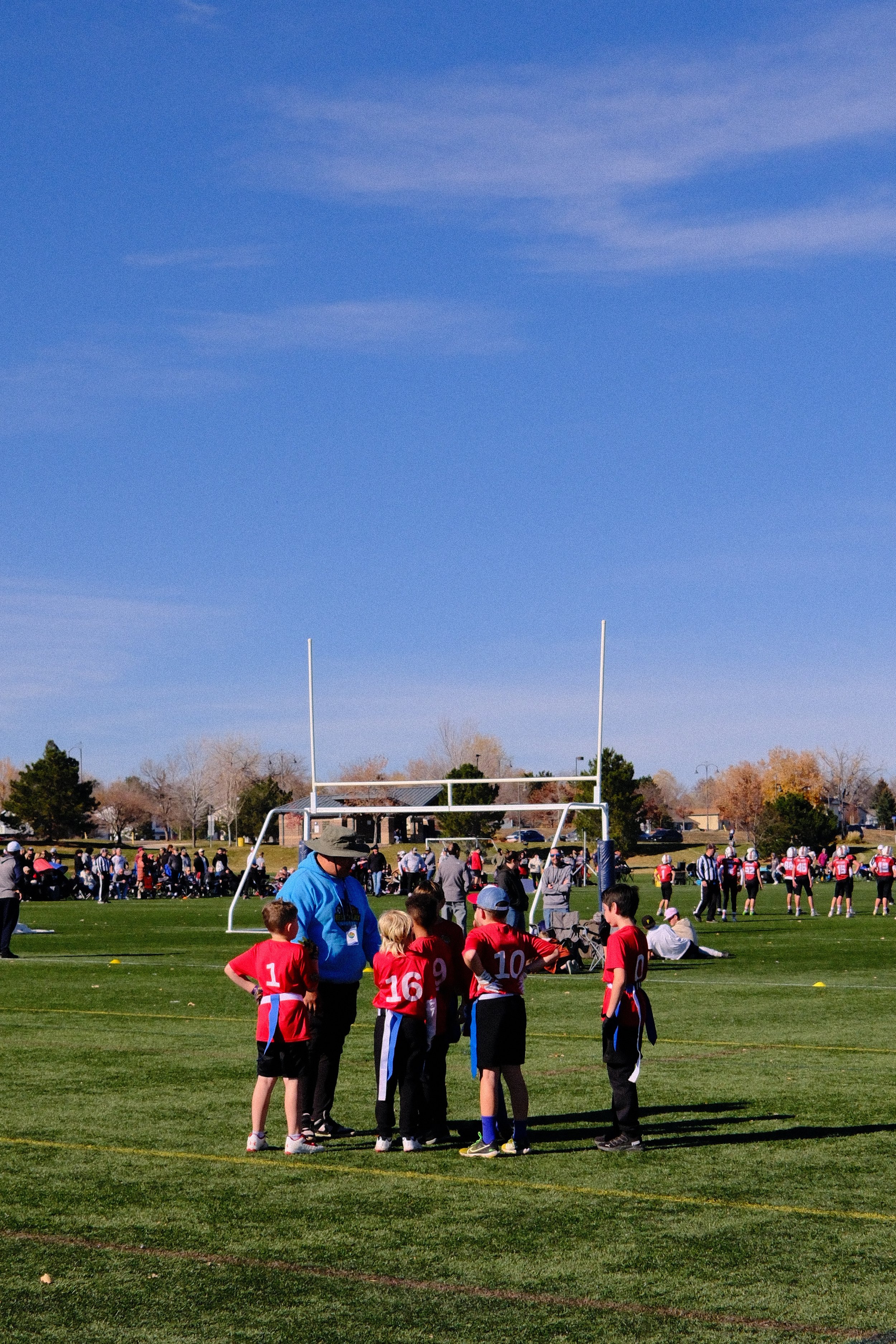 Youth football team huddle on a sunny field Broomfield Colorado.