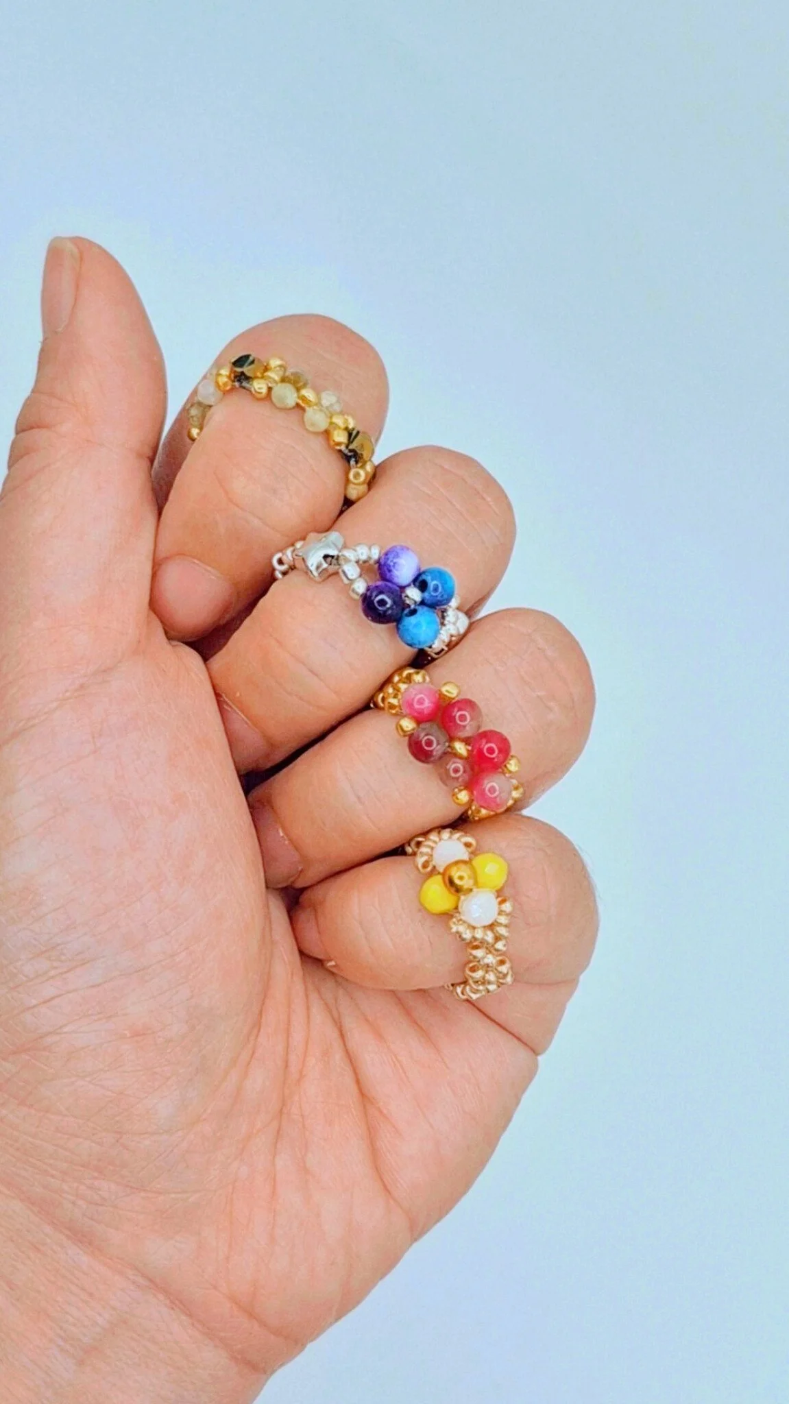 someone wearing several natural gemstone beaded rings