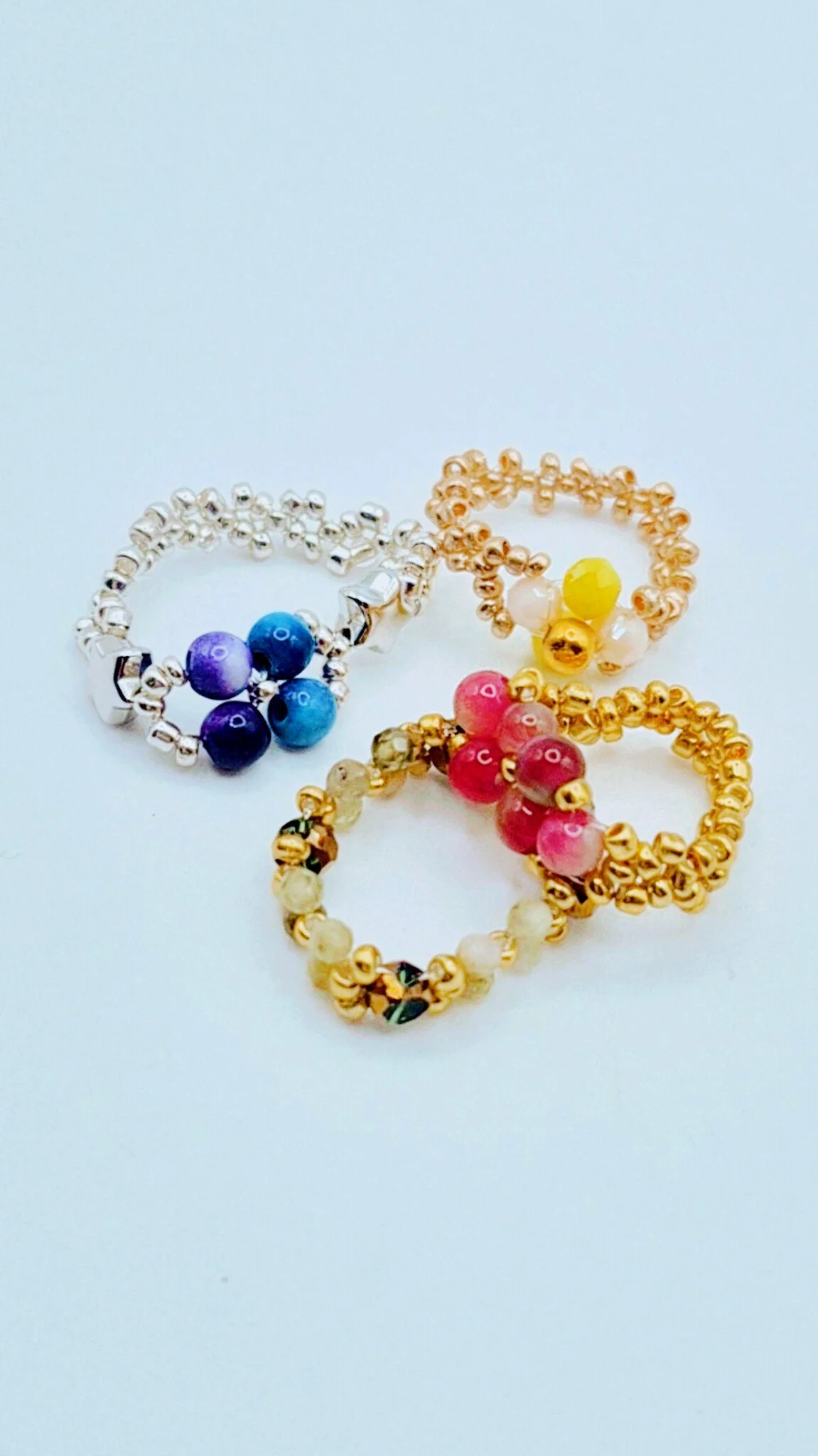 a set of 4 colorful beaded flower rings with metal and gemstone beads