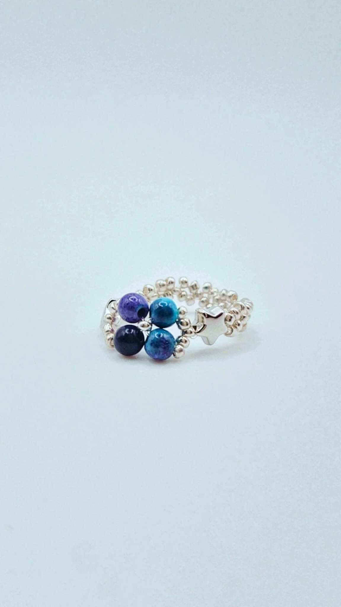 a silver beaded ring with purple blue natural stone beads flower