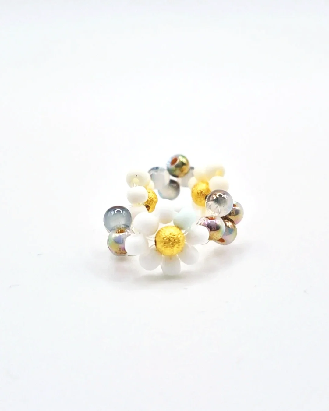 a stretchable hand beaded ring mimicking white petaled daisy flowers with silver-gold glass beads