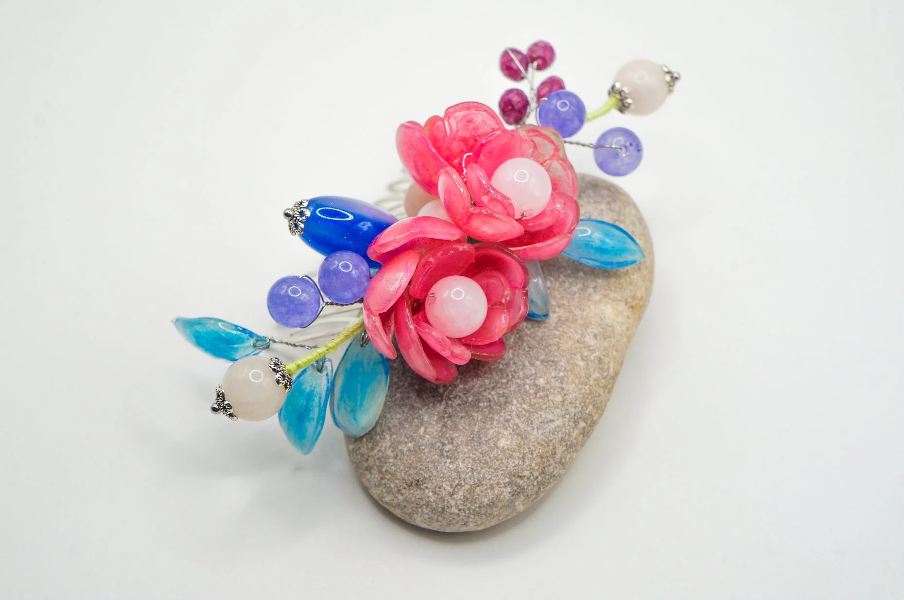 sideview of a large silver haircomb featuring pink peony and sky blue leaves with various gemstones