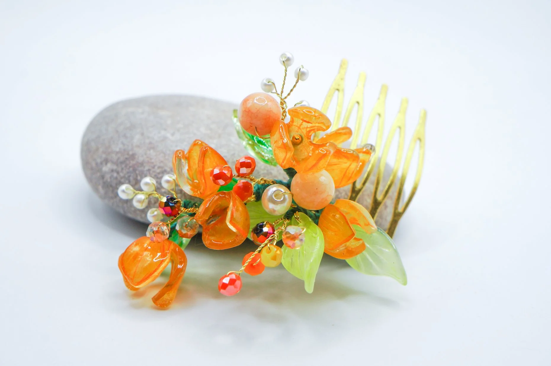 a handmade small golden haircomb with orange flower buds, imitation pearls, and glass leaves