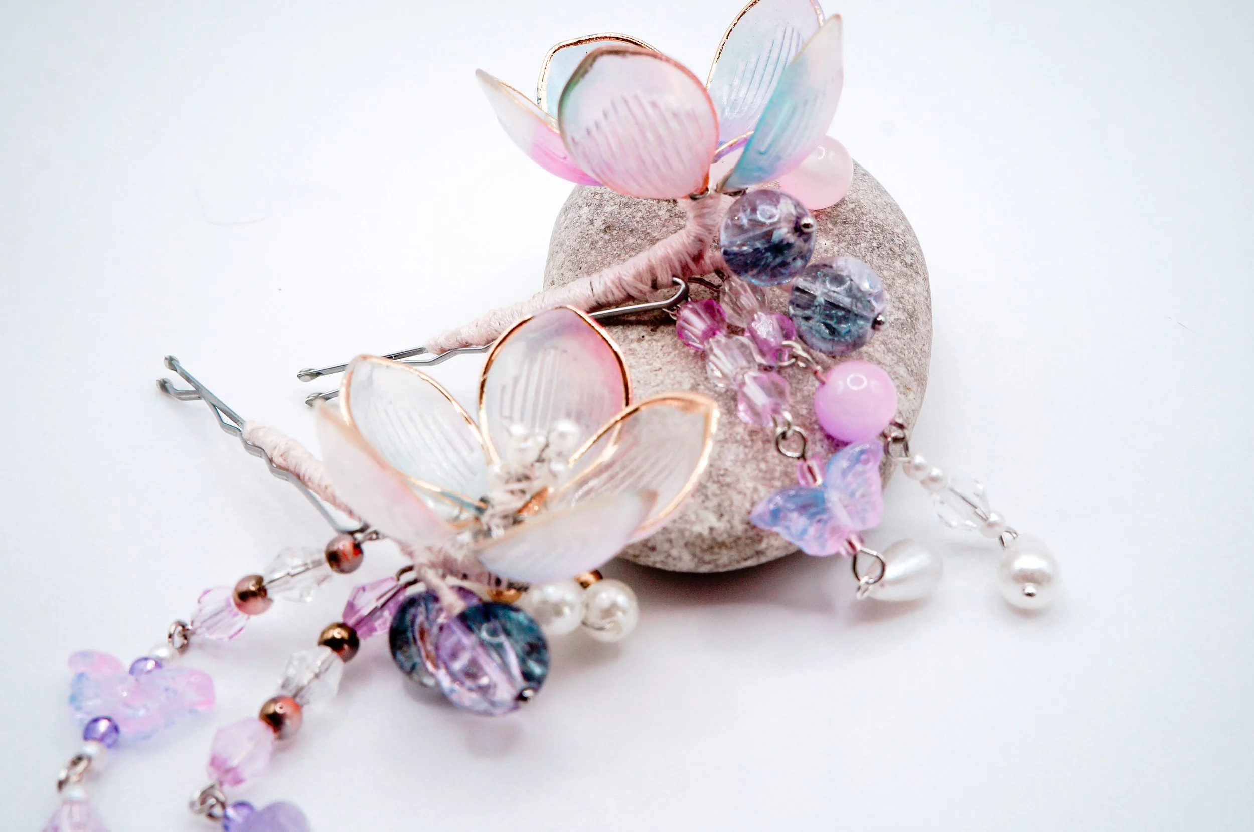 a pair of cherry blossom bobby pins with glass and natural stone beads displayed on a rock