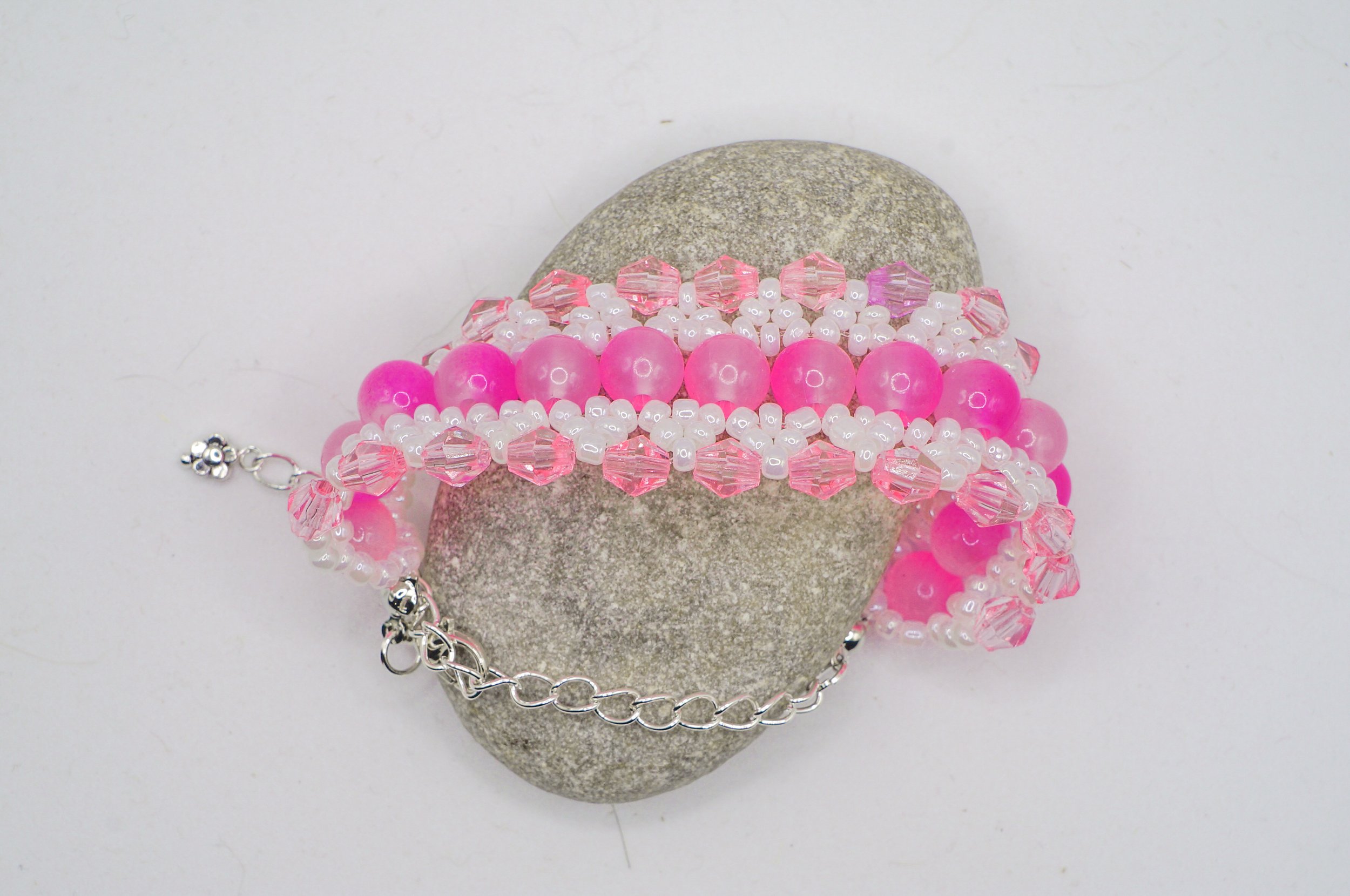 a beaded bangle using pink gradient glass beads, silver seed beads, and pink bicone crystals