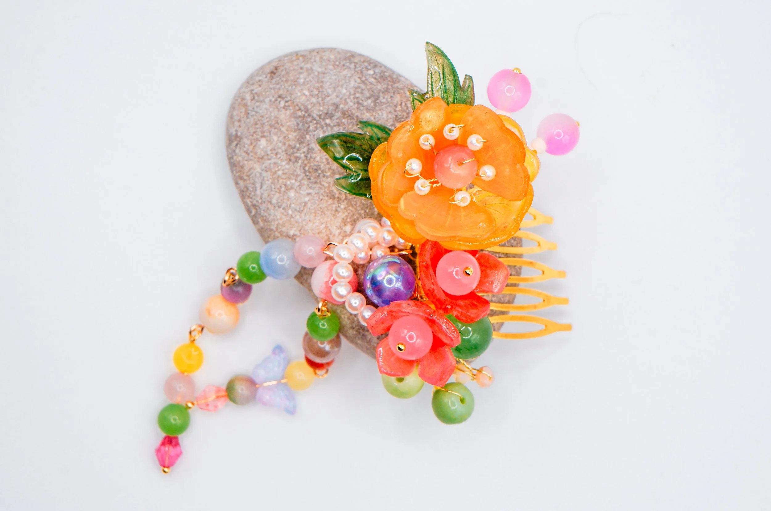 Top view of a gold hand crafted Chinese hair comb with peach flower and gold rose motif with beaded tassels