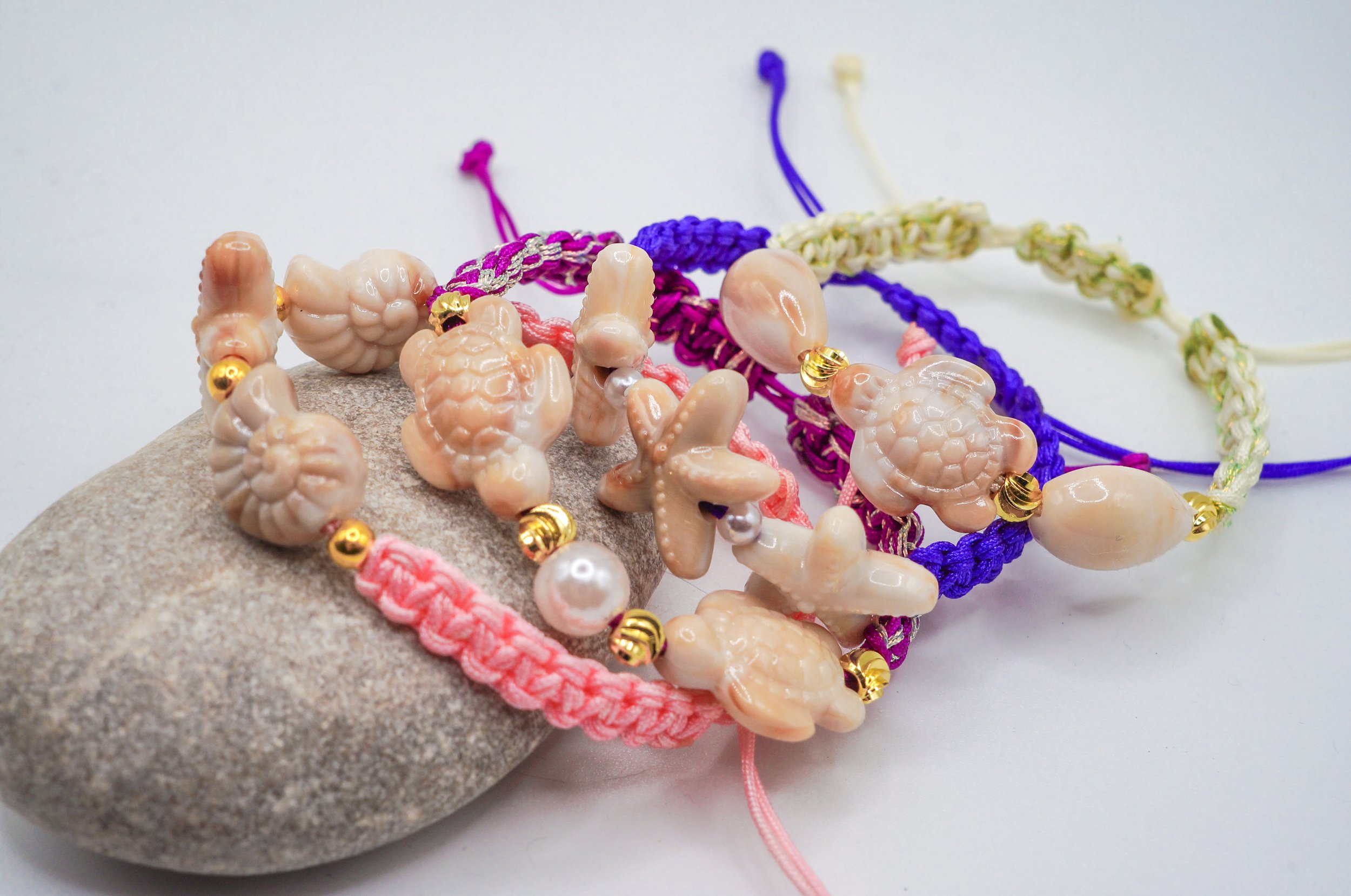 a set of hand-woven chinese macrame bracelets with seashell charms