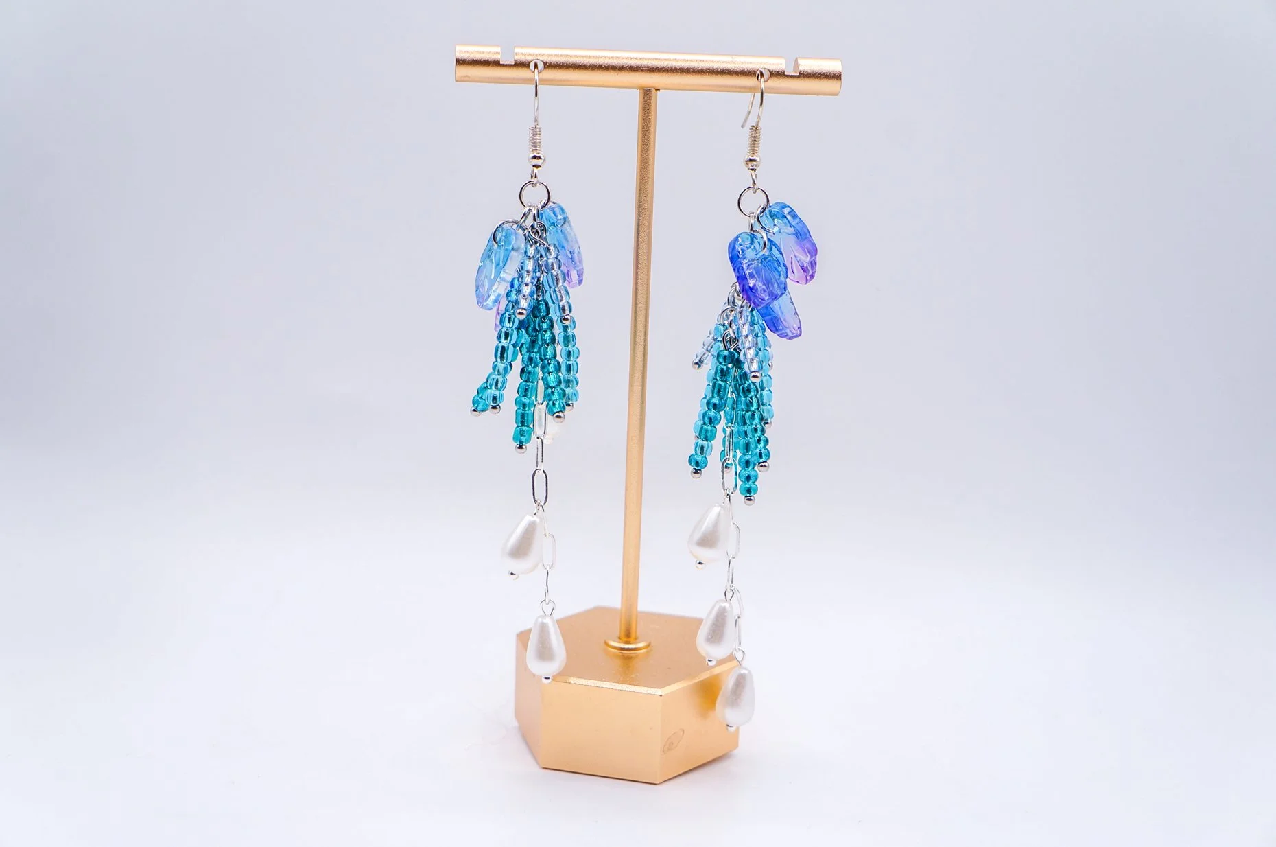 close-up of a pair of hand beaded blue wisteria earrings with silver-plated hooks