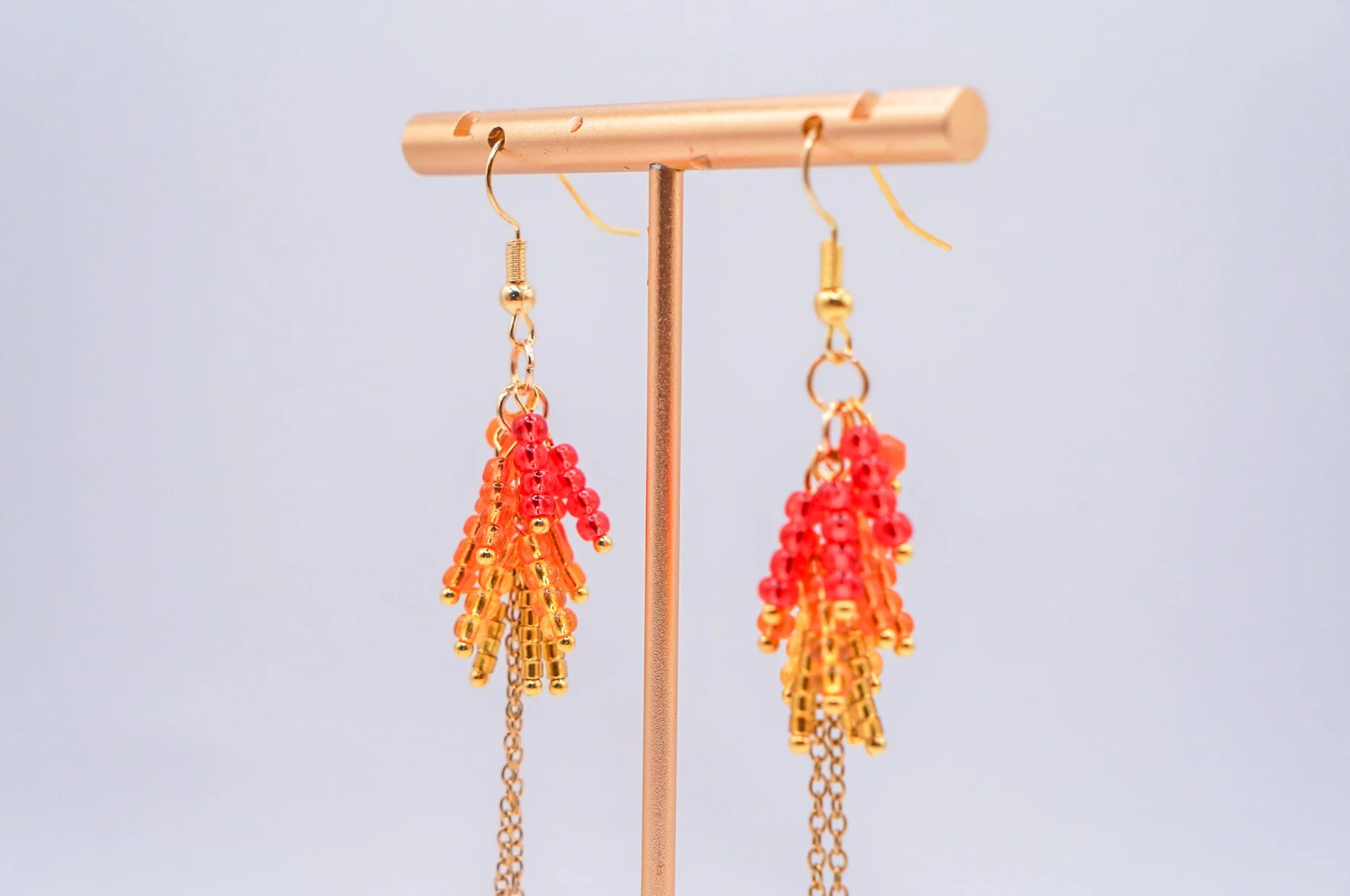 close-up of a pair of hand beaded red wisteria earrings with gold-plated hooks
