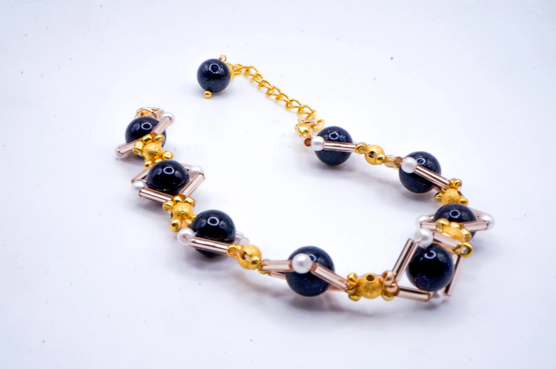 An elegant beaded bracelet inspired by the Baroque Era featuring gold glass tube beads, metal beads, and black natural stone beads that shine like a starry sky.