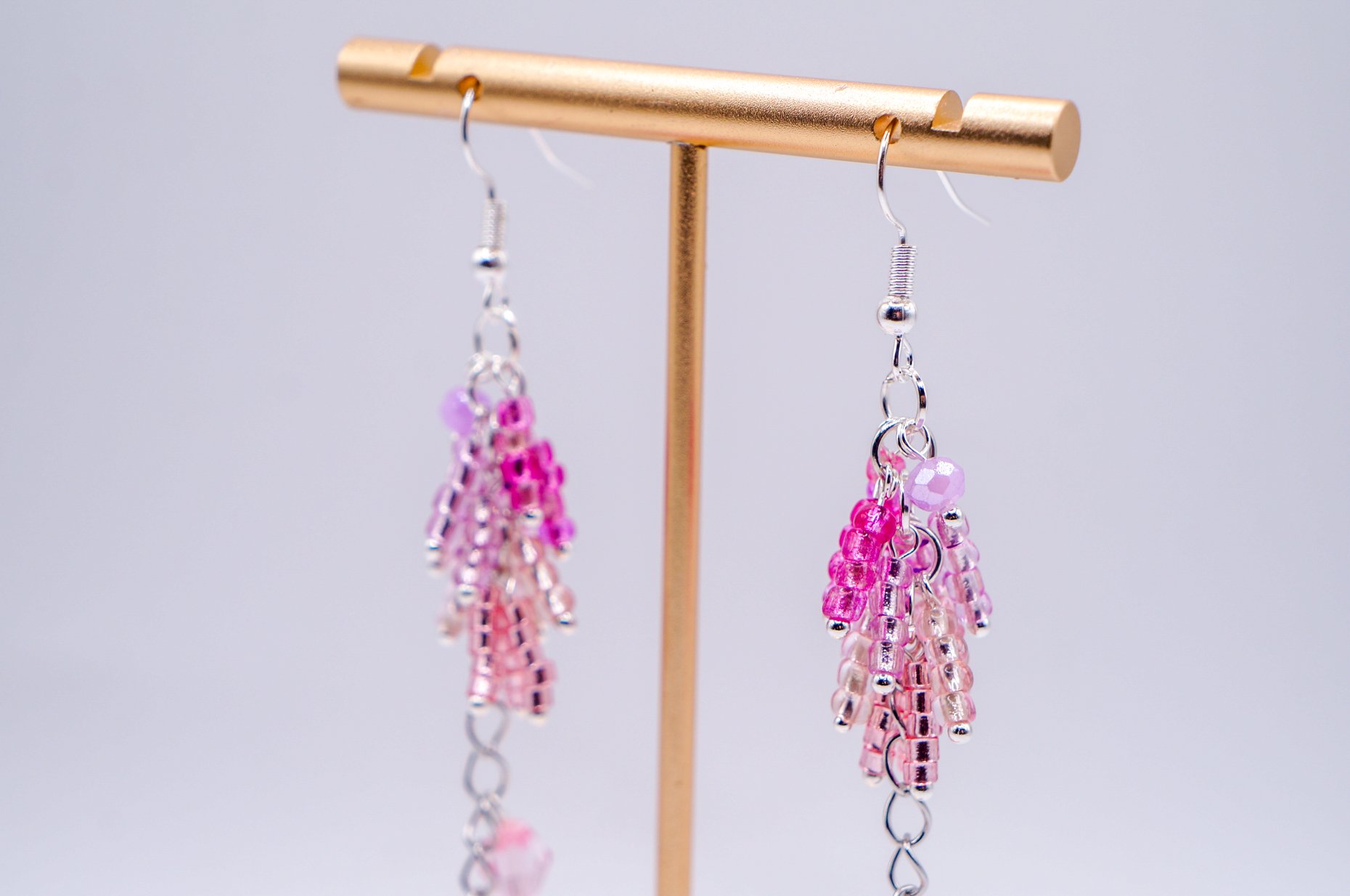 close-up of a pair of pink and violet hand beaded wisteria earrings with silver-plated hooks