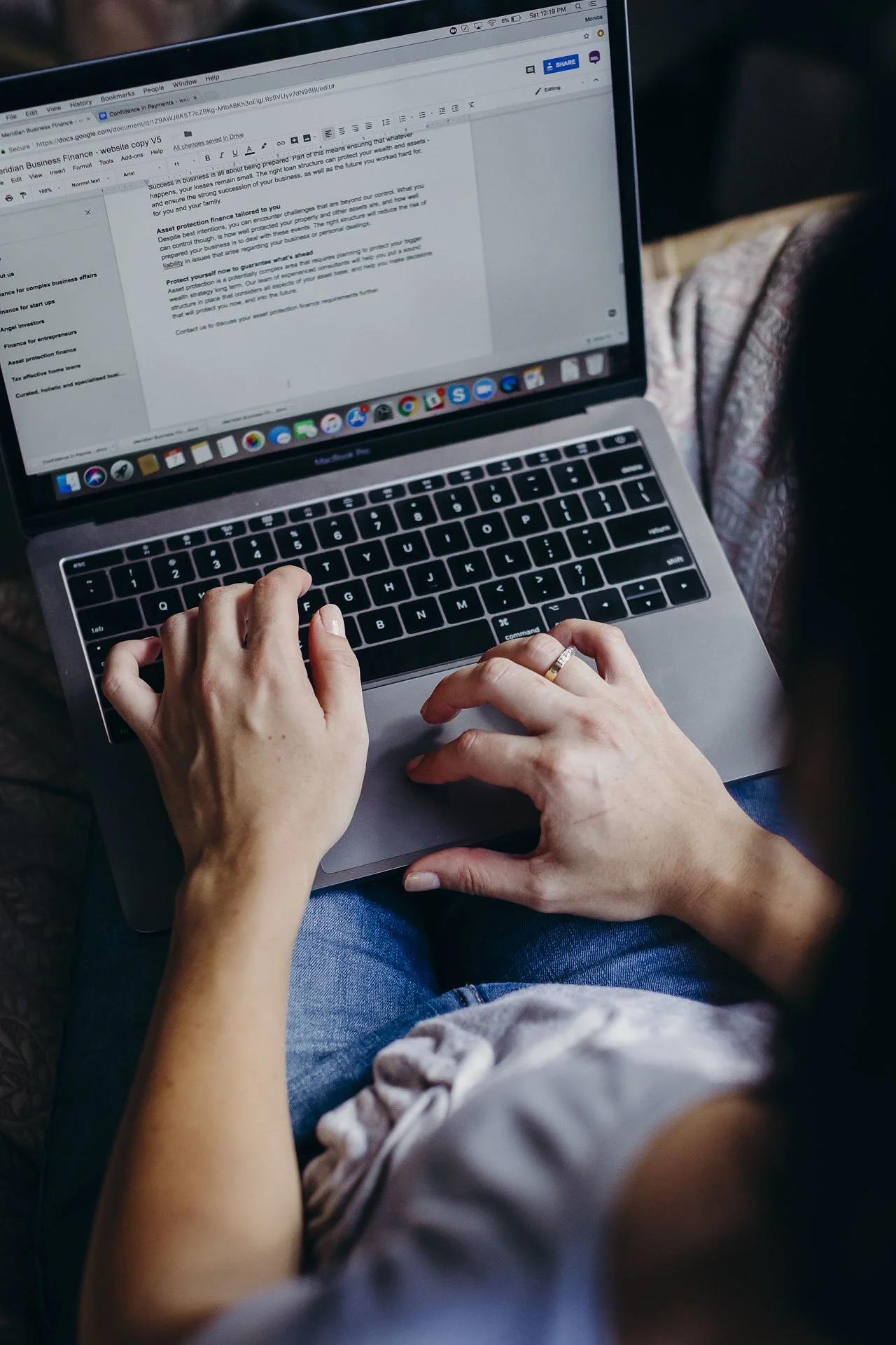 Person typing on a MacBook laptop with a document open on the screen.