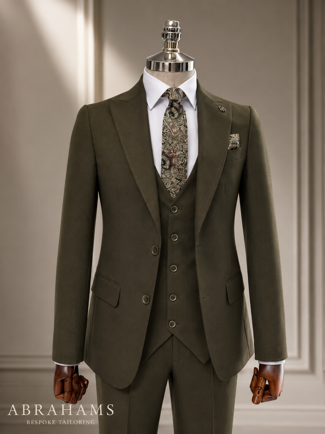 Terno clássico verde escuro com gravata de padrão paisley, vestido em manequim, em ambiente de loja de roupas de alta costura.