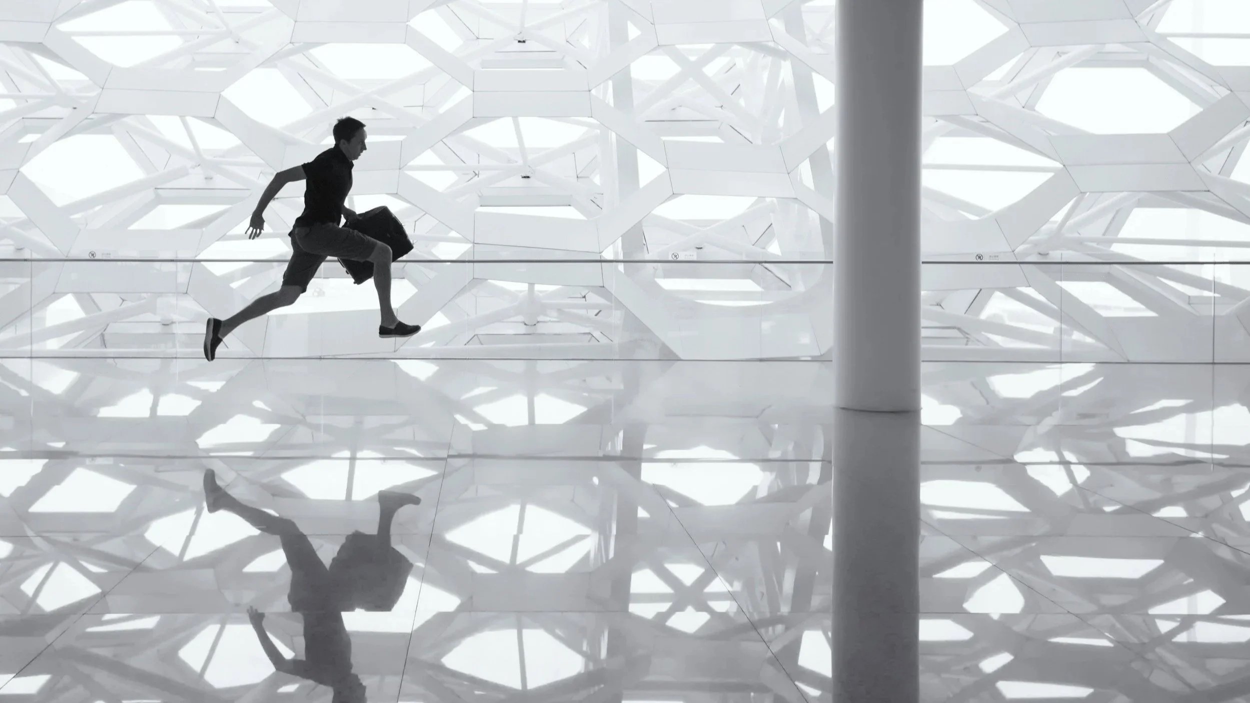 Persona trabajando en una computadora portátil en una mesa de oficina, con una taza de café con arte en espuma, un teléfono inteligente y algunos bolígrafos y notas.