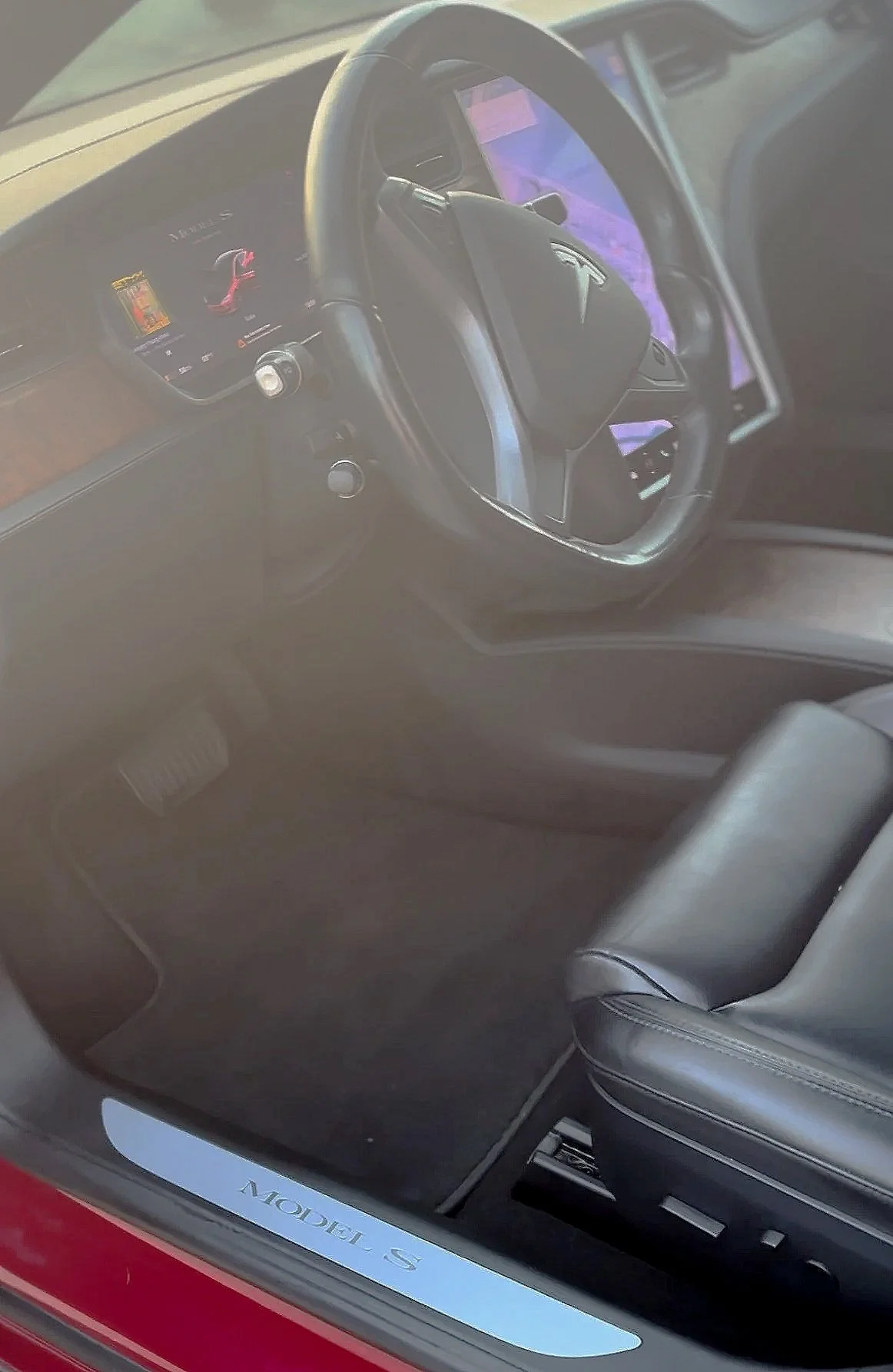 Interior of a Tesla Model S, showing the steering wheel, digital dashboard, and front passenger seat