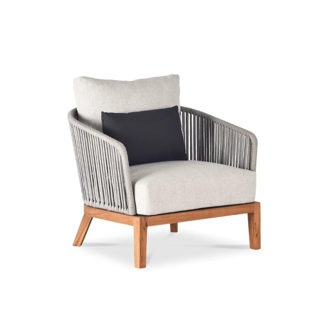 Elegant living room with a beige sofa, two matching armchairs, a black coffee table, a large beige rug, wooden wall paneling, and two modern wall-mounted lamps, with curtains allowing natural light to enter.