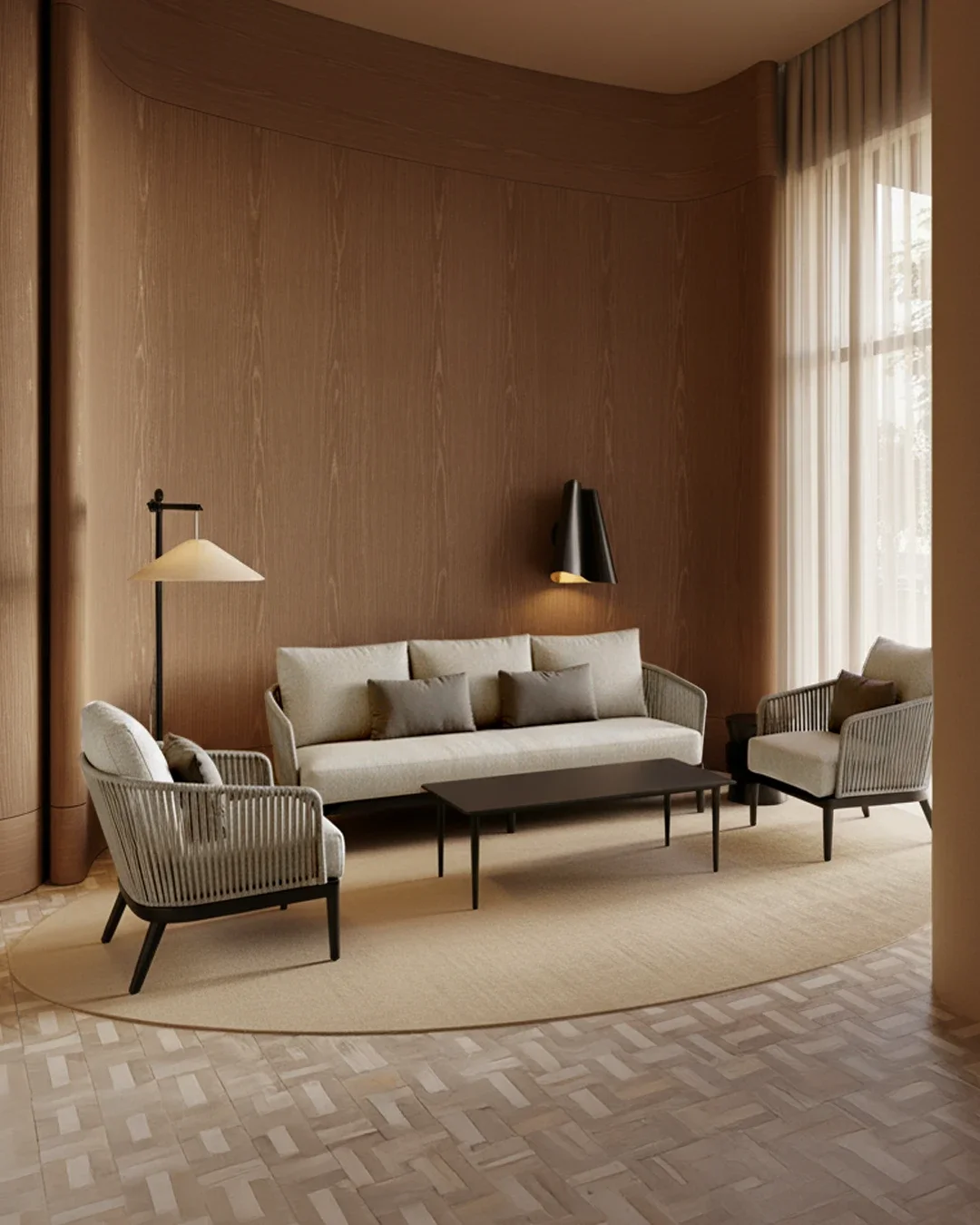 Modern seating area with a cream sofa, two matching armchairs, and a black coffee table, set on a light beige oval rug. A wooden-paneled wall behind the sofa features two contemporary wall-mounted lights, with sheer curtains on a large window to the right.