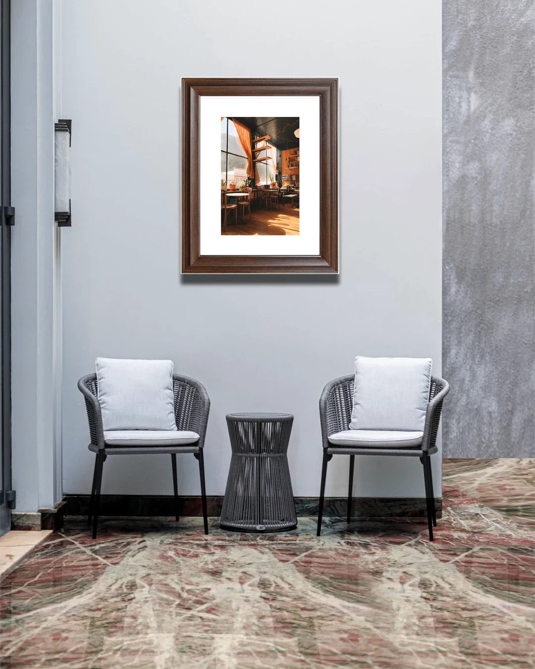 Two chairs with white cushions and a small black side table are placed against a white wall in a waiting area. A framed picture of a cozy cafe interior hangs on the wall above.