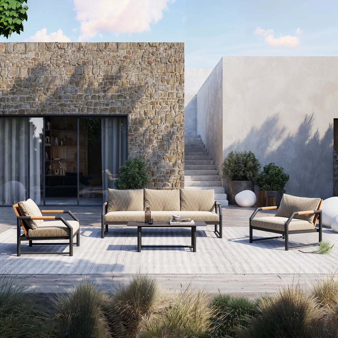 Outdoor patio with modern furniture including a beige sofa and two armchairs with wooden armrests, a dark coffee table, and various plants in pots, against a backdrop of a stone and white stucco wall with stairs and sliding glass doors.