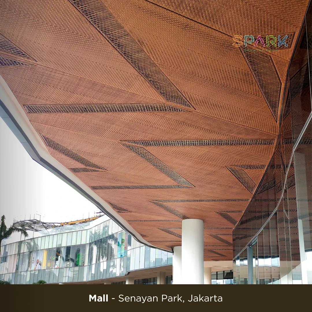 Modern shopping mall ceiling with intricate geometric wooden panels and ventilation grilles, with a reflection on glass walls and a sign reading 'PARK' in colorful neon lights.