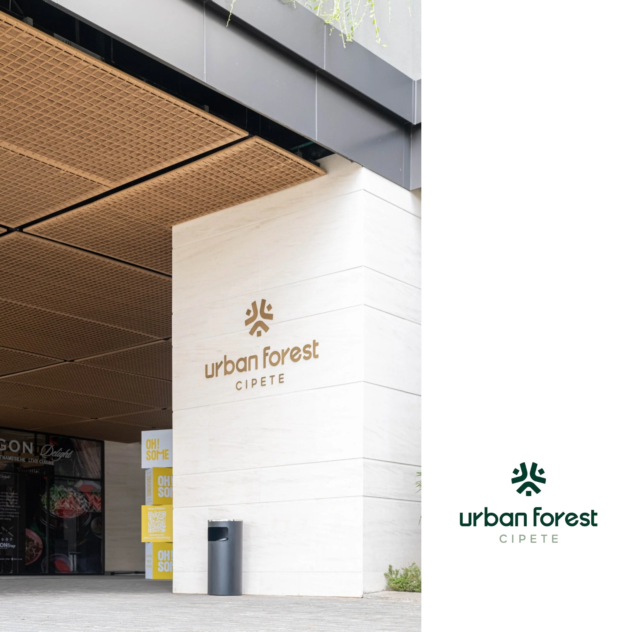 Exterior of a building with a sign that reads 'urban forest CIPETE' and a logo above it, featuring a stylized tree design. The building has a modern design with a beige stone wall, a wooden ceiling, and a trash bin in front.