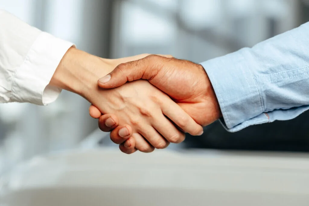 Two people shaking hands in a professional setting.