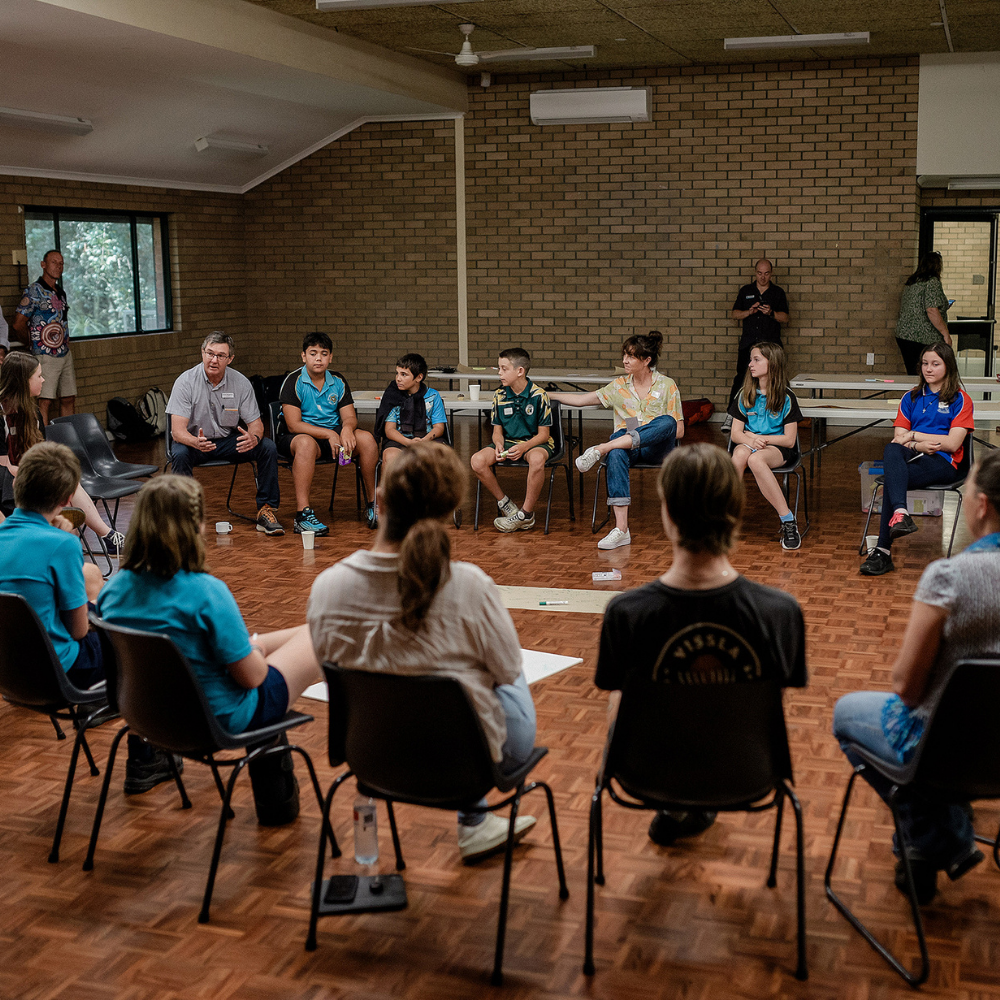 young people sitting in a circle on chairs talking to each other