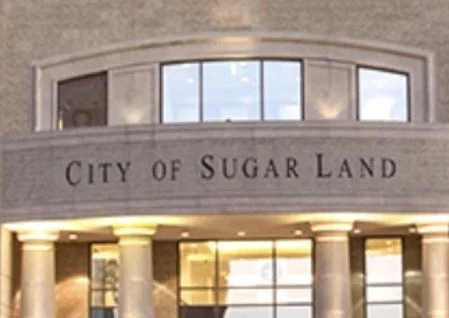 City of Sugar Land sign above the illuminated entrance to Sugar Land City Hall, Texas.