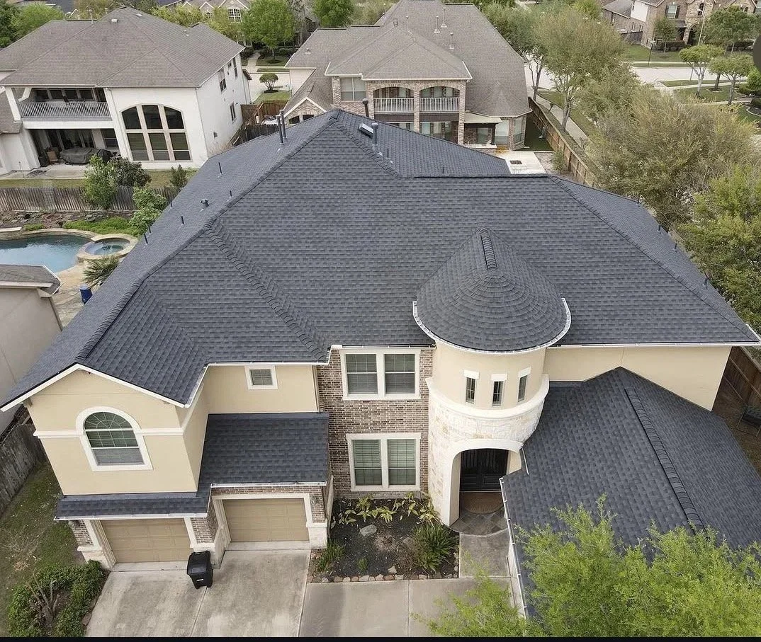 Aerial view of a completed gray shingle roof replacement on a two-story home in Katy, Texas, by Apex Roofing Solutions.