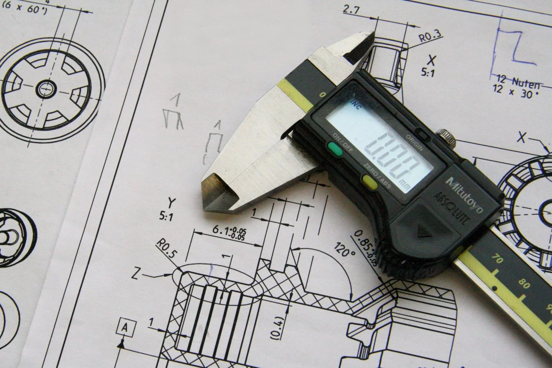 Technical engineering drawing with detailed measurements, accompanied by a digital caliper showing a reading of 10.00 mm.